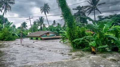 A photograph of a submerged house in Philippines, the flood water has almost complete submerged the building.